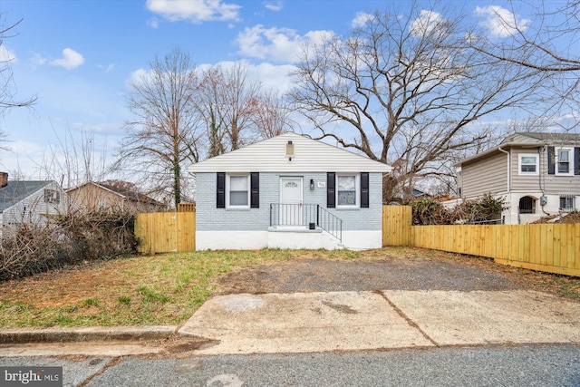 bungalow-style house with brick siding, fence, and a gate