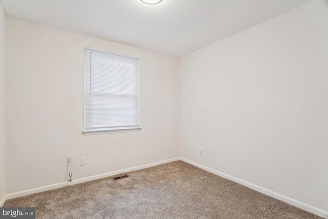 carpeted spare room with visible vents and baseboards