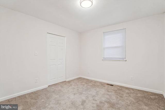 empty room featuring visible vents, carpet floors, and baseboards