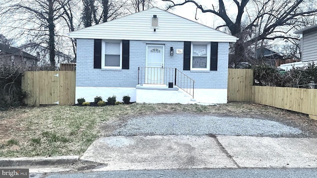 bungalow featuring brick siding and fence