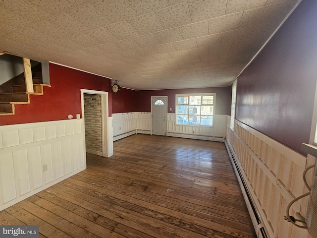 interior space featuring a baseboard heating unit, stairs, wainscoting, wood-type flooring, and a baseboard radiator