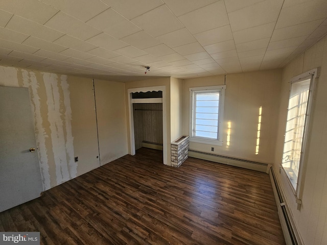 unfurnished bedroom with a baseboard heating unit and wood finished floors