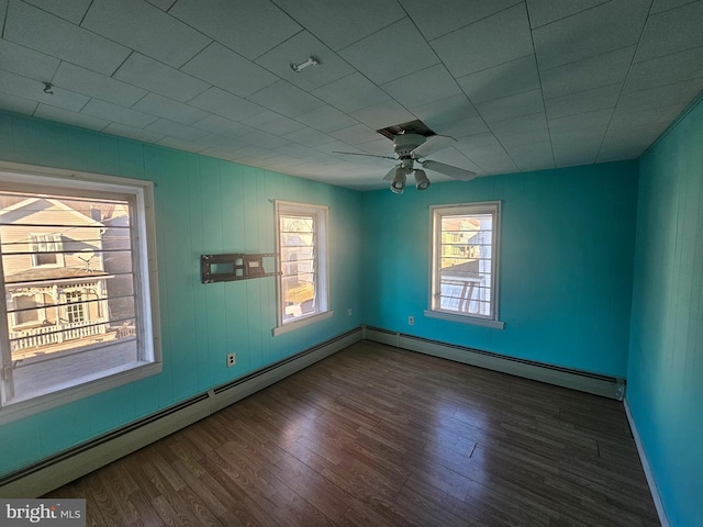 unfurnished room with baseboards, a baseboard heating unit, a ceiling fan, and wood finished floors