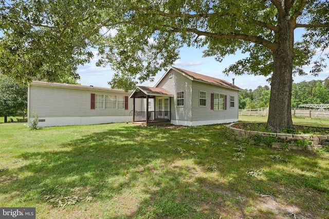 rear view of property featuring crawl space, a lawn, and fence