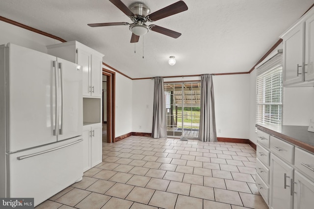 kitchen featuring white cabinetry, a ceiling fan, freestanding refrigerator, and ornamental molding