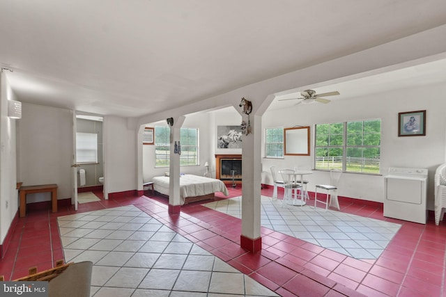 bedroom featuring tile patterned floors, a glass covered fireplace, and washer / clothes dryer