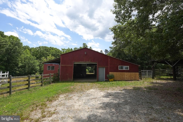 view of pole building featuring fence and driveway