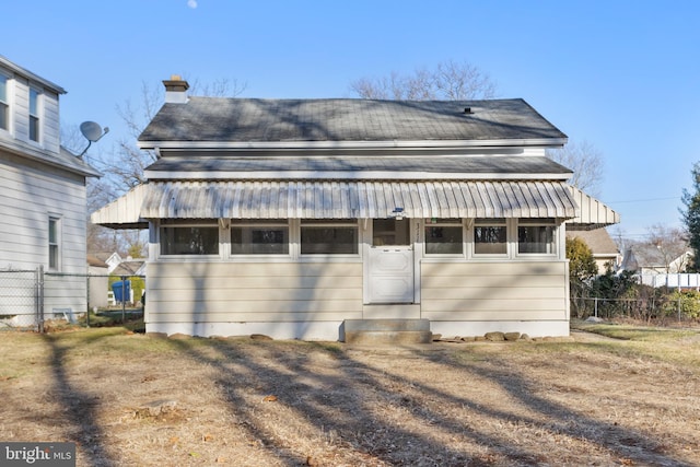 back of property featuring entry steps, a chimney, and fence