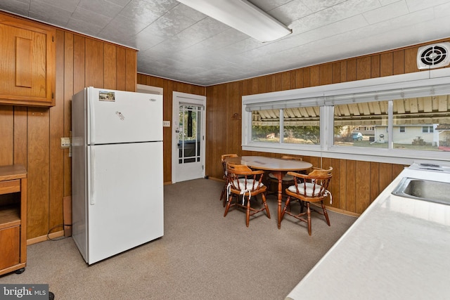 dining area with light carpet and wood walls