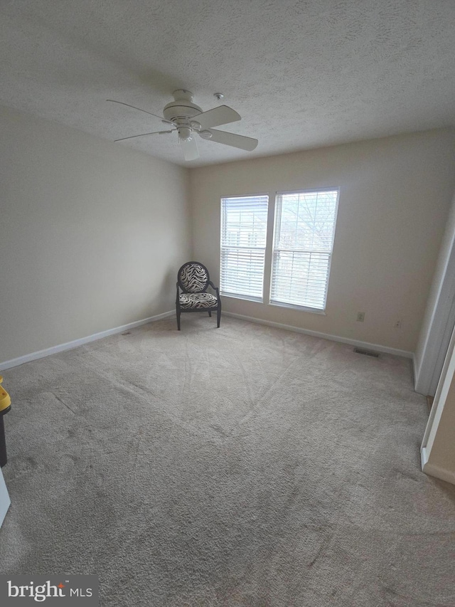 unfurnished room featuring baseboards, carpet floors, a textured ceiling, and a ceiling fan