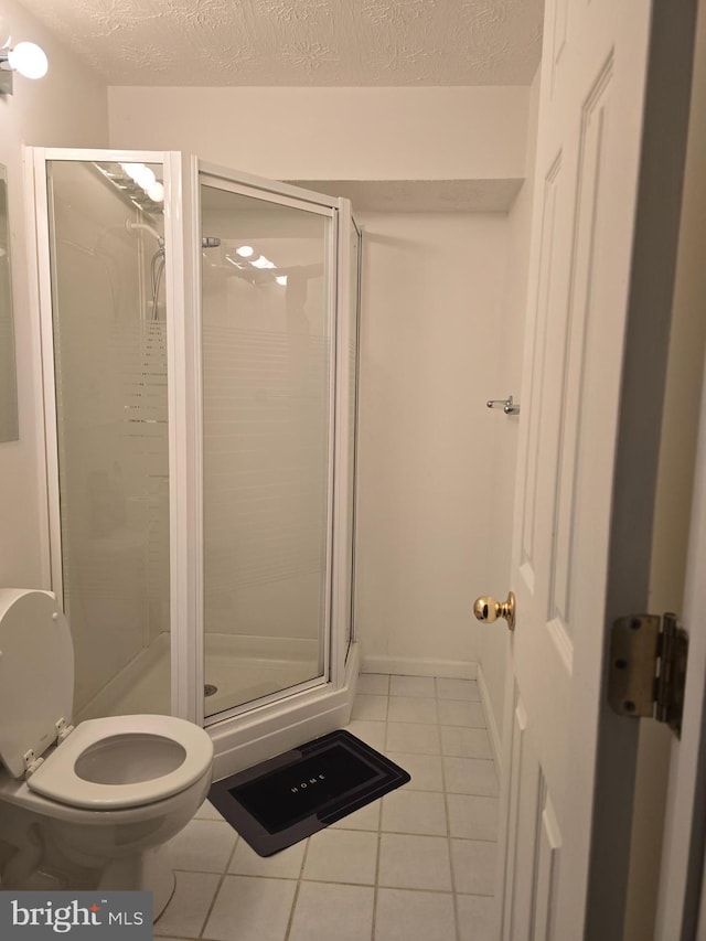 full bathroom with tile patterned flooring, a shower stall, and a textured ceiling