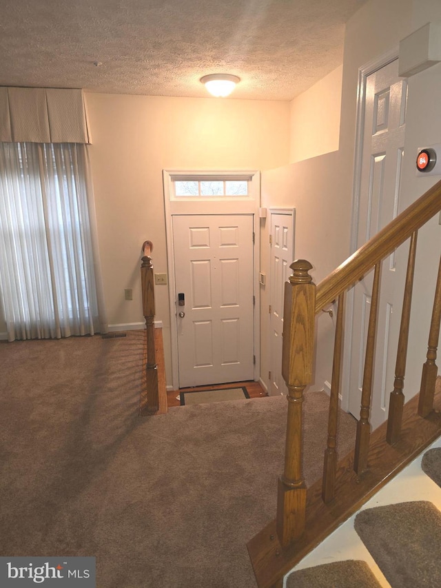 carpeted foyer with stairway and a textured ceiling