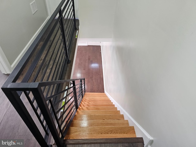 stairway with visible vents, baseboards, and wood finished floors