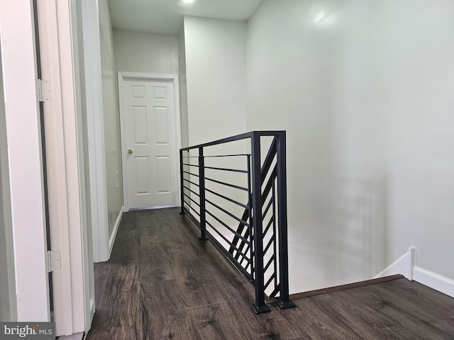 corridor featuring an upstairs landing, baseboards, and dark wood-style flooring