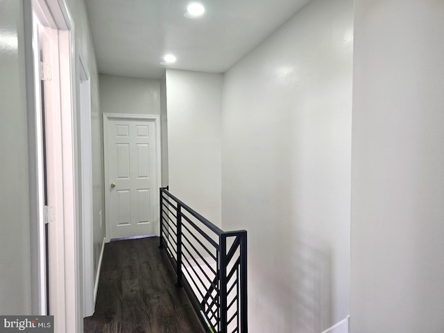 hall with recessed lighting, an upstairs landing, and dark wood-style flooring