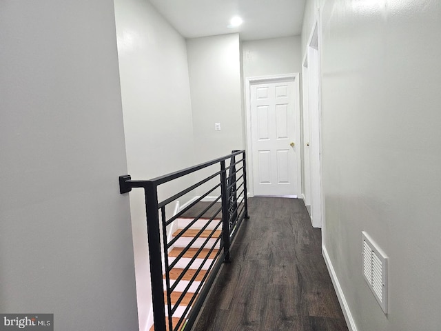 corridor with visible vents, an upstairs landing, baseboards, and dark wood finished floors