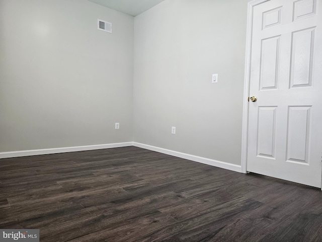 empty room featuring dark wood-style floors, visible vents, and baseboards