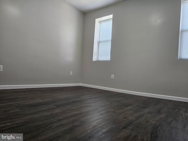 unfurnished room featuring dark wood-type flooring and baseboards