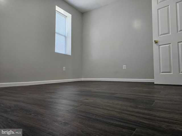 spare room featuring dark wood-style floors and baseboards