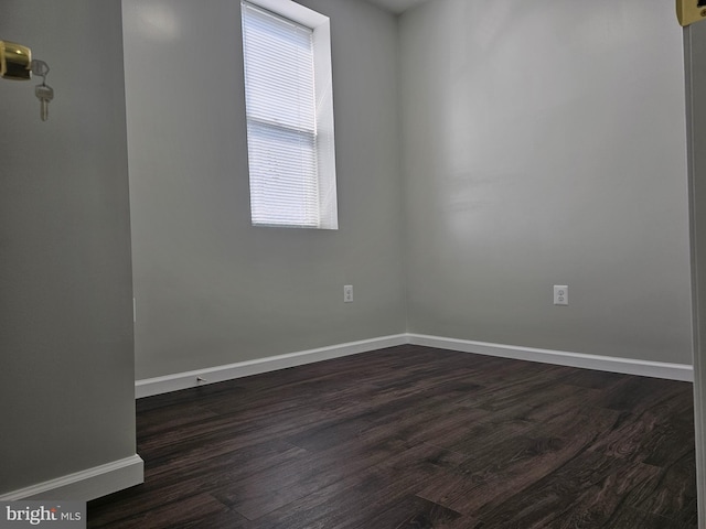 unfurnished room with dark wood finished floors and baseboards