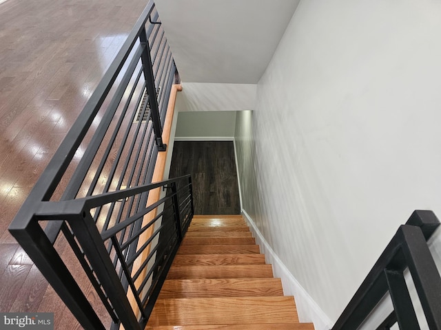 staircase featuring wood finished floors and baseboards