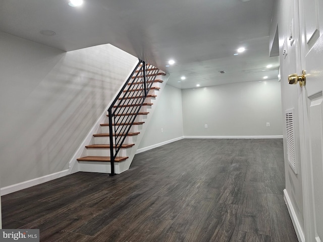 below grade area with stairs, dark wood-type flooring, recessed lighting, and baseboards