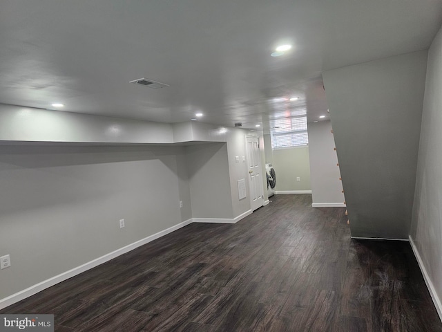 below grade area featuring visible vents, washer / clothes dryer, dark wood-style floors, recessed lighting, and baseboards