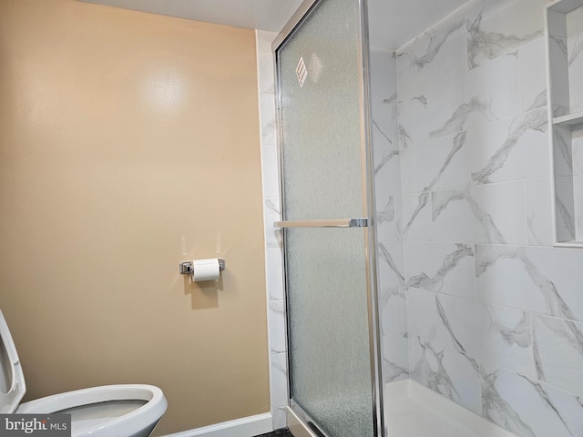 bathroom with a shower stall, toilet, and baseboards