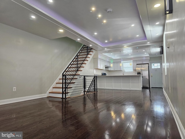 unfurnished living room featuring baseboards, dark wood-style flooring, and a sink