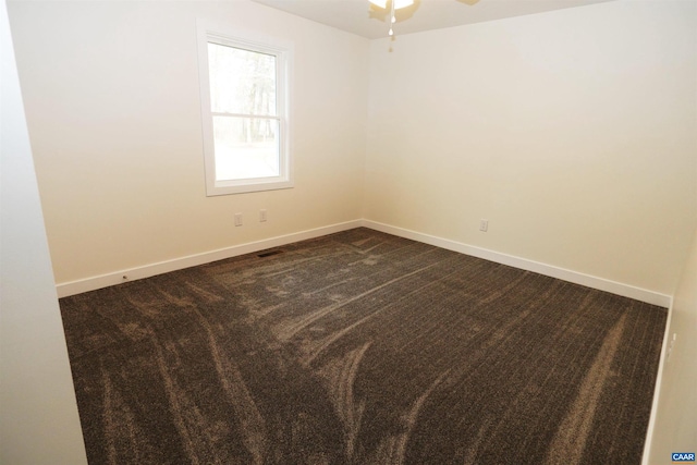 empty room featuring dark colored carpet, baseboards, and ceiling fan