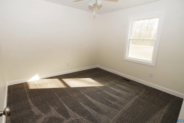 unfurnished room with visible vents, a ceiling fan, dark colored carpet, and baseboards