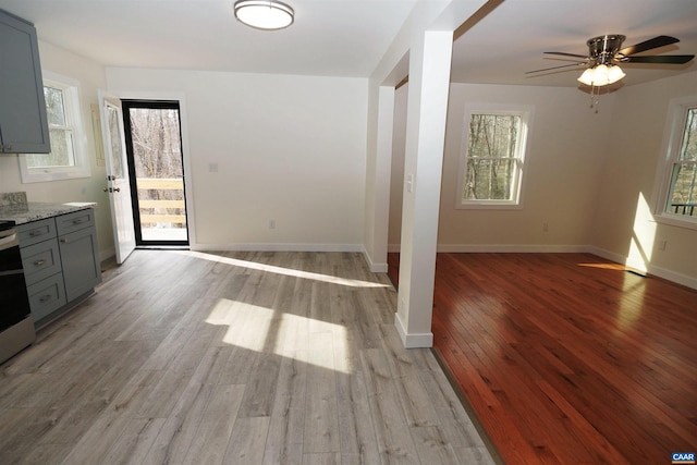 unfurnished dining area with a wealth of natural light, baseboards, light wood-style floors, and ceiling fan