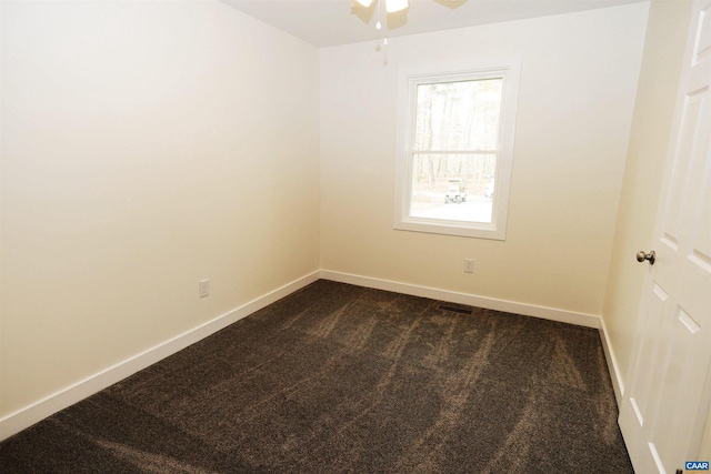 unfurnished room with dark colored carpet, visible vents, baseboards, and a ceiling fan