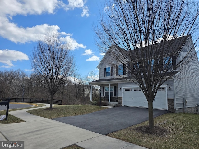 view of front facade featuring an attached garage, fence, a front yard, stone siding, and driveway