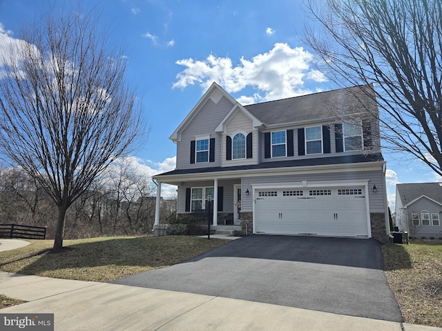 view of front of house with a front yard, an attached garage, covered porch, stone siding, and aphalt driveway