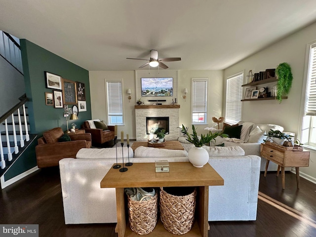 living room featuring dark wood finished floors, stairway, a fireplace, and ceiling fan