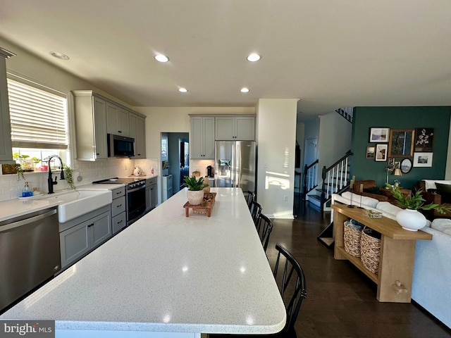 kitchen with tasteful backsplash, open floor plan, gray cabinets, stainless steel appliances, and a sink