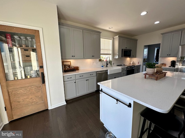 kitchen with gray cabinets, recessed lighting, appliances with stainless steel finishes, light countertops, and dark wood-style flooring