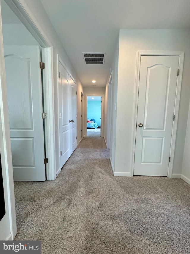 corridor with carpet, visible vents, and baseboards