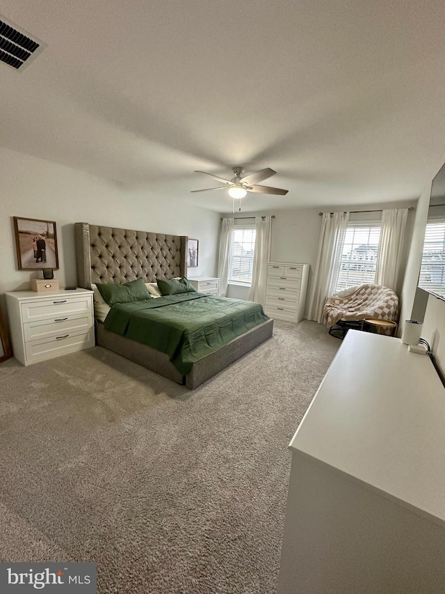 bedroom with visible vents, multiple windows, carpet, and a ceiling fan