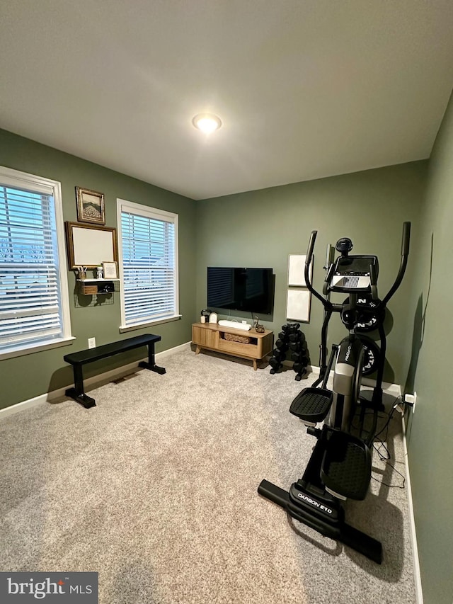 exercise area featuring carpet, baseboards, and a wealth of natural light