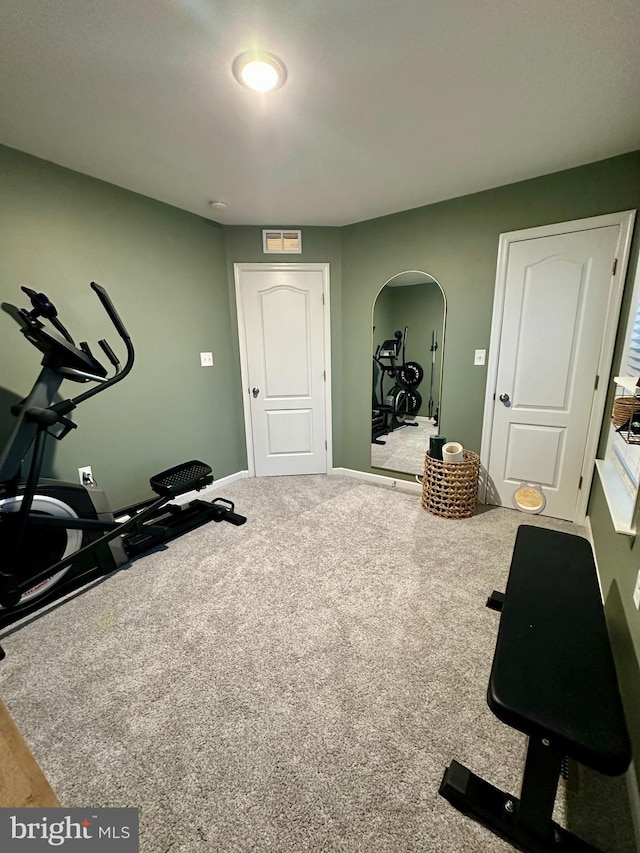 workout area with baseboards, arched walkways, and carpet floors