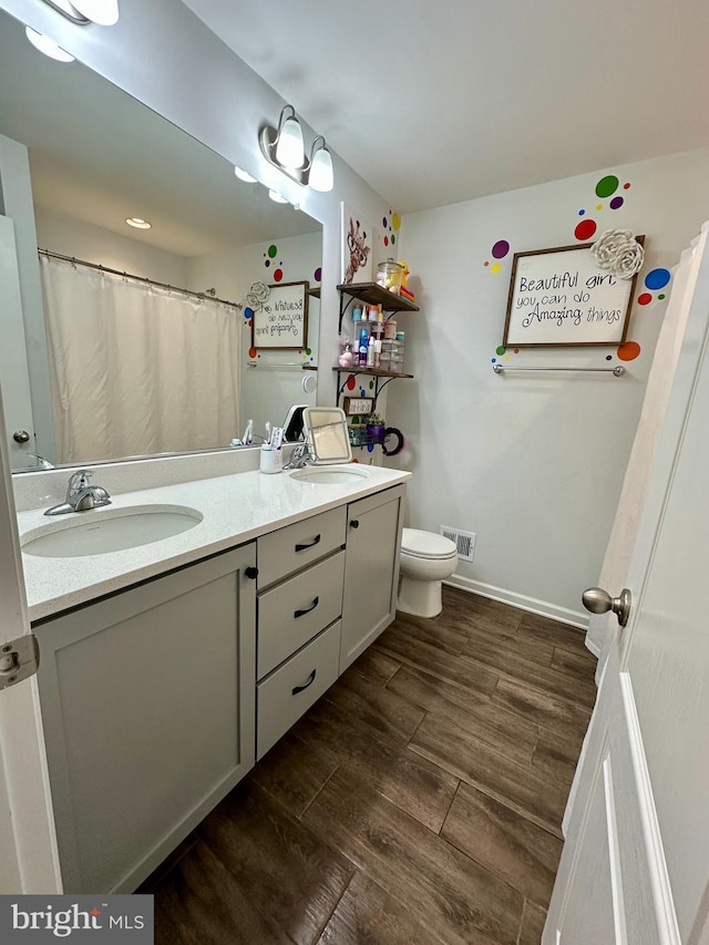 full bath with toilet, wood finished floors, visible vents, and a sink