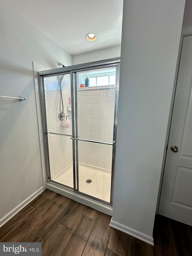 bathroom featuring a shower stall, wood finished floors, and baseboards