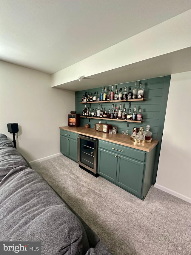 bar featuring baseboards, a bar, beverage cooler, and carpet flooring