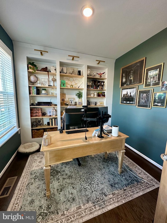 office area with built in shelves, visible vents, baseboards, and wood finished floors