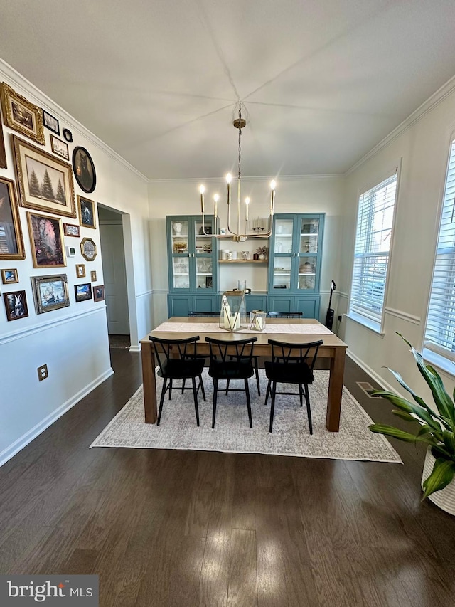 dining room with a notable chandelier, dark wood-style floors, baseboards, and ornamental molding