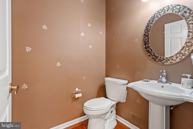 half bathroom with toilet, visible vents, and baseboards