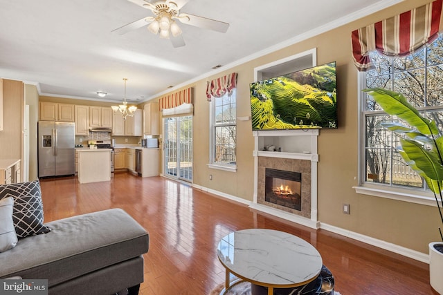 living room featuring baseboards, a fireplace, light wood-type flooring, and ornamental molding