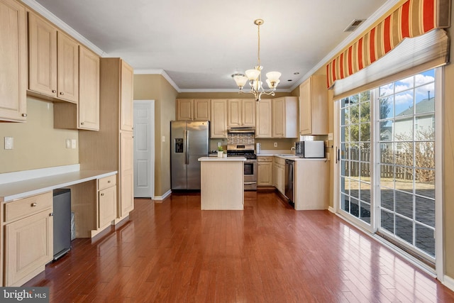 kitchen with visible vents, a center island, under cabinet range hood, appliances with stainless steel finishes, and an inviting chandelier